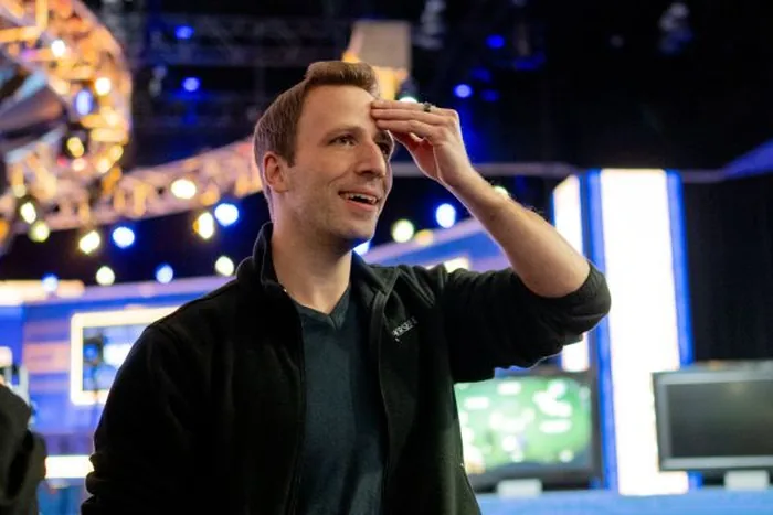 Benny Glaser Early Career Benny Glaser smiling with a hand on his forehead under tournament stage lights