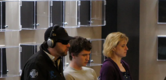 Phil Hellmuth and Kathy Sanborn on the Rail Phil Hellmuth in a black cap and headphones at a poker tournament with his wife Kathy Sanborn watching from the rail