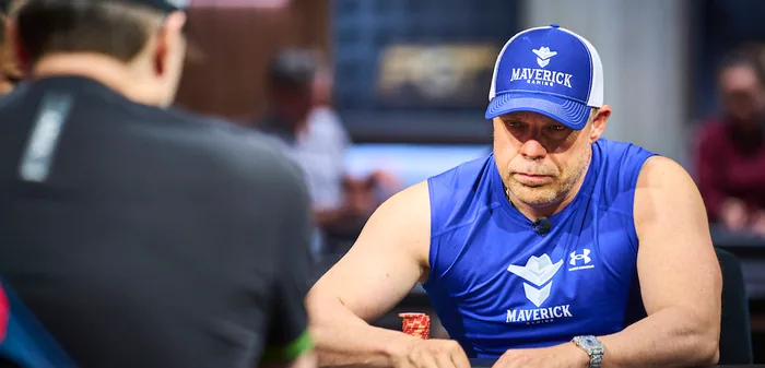 Eric Persson wearing blue Maverick Gaming branded gear while studying the action at a poker table