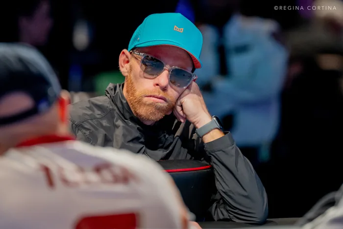 Jamie Shaevel resting his head on his hand at the WSOP 2026 Main Event final table, wearing sunglasses and a teal cap