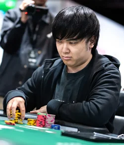 Masato Yokosawa at a poker tournament table reaching for chips