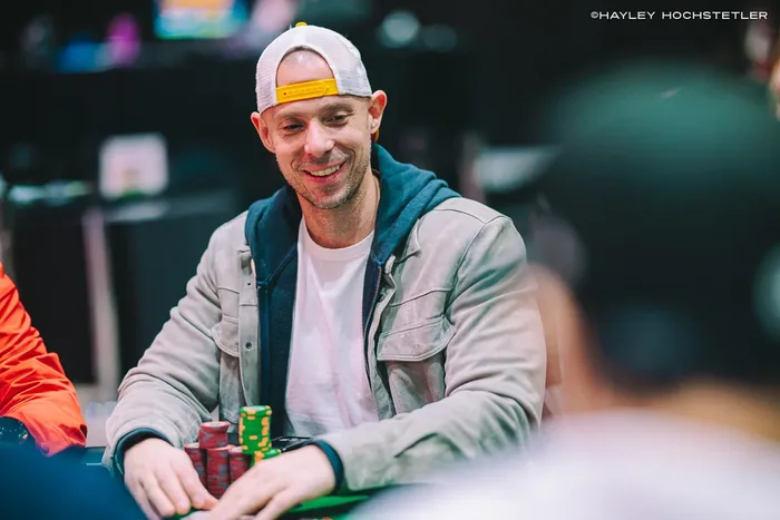 Matt Berkey smiling behind a stack of chips at a tournament table