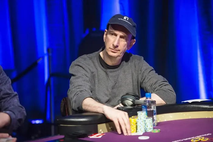 Erik Seidel at the poker table during a high-stakes tournament with blue stage lighting