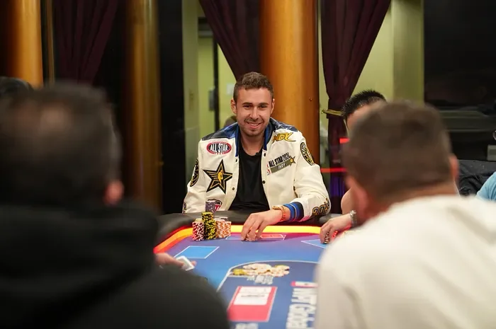 Sean Perry smiling at a live poker cash game table wearing an All-Star jacket