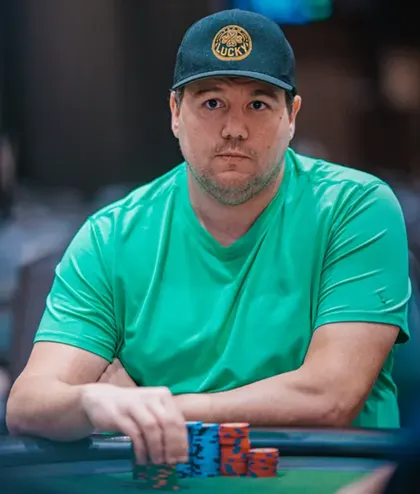Shaun Deeb at the poker table wearing a green t-shirt and Lucky cap with chips