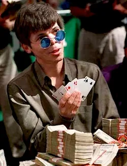 Stu Ungar holding his cards behind the 1997 WSOP Main Event prize money