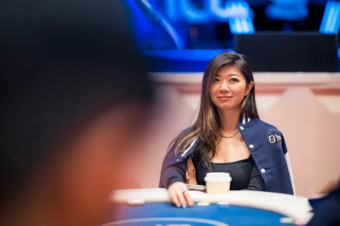 Xuan Liu at a poker table wearing a WPT jacket under blue stage lighting