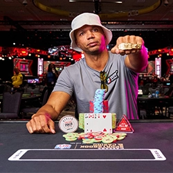 Phil Ivey showing his WSOP bracelet at the poker table with chips and cards in front of him