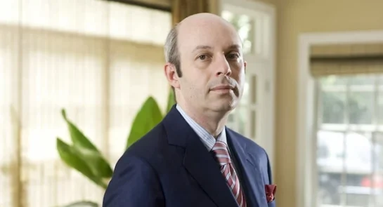 Tom Goldstein, prominent U.S. Supreme Court litigator and SCOTUSblog founder, standing in a formal office setting wearing a navy suit, light blue striped shirt, red-and-white striped tie, and red pocket square, with a serious expression.