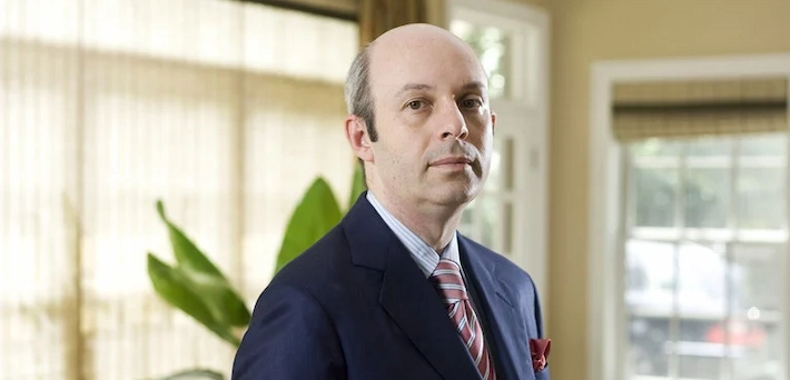 Tom Goldstein, prominent U.S. Supreme Court litigator and SCOTUSblog founder, standing in a formal office setting wearing a navy suit, light blue striped shirt, red-and-white striped tie, and red pocket square, with a serious expression.