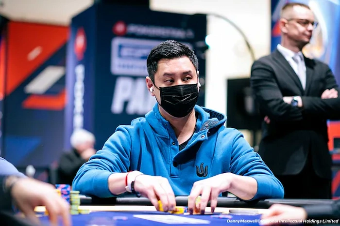 Punnat Punsri Punnat Punsri, Thai high-stakes poker pro, masked and focused at the EPT Paris table in a blue hoodie, handling chips with stacked towers in front, branded PokerStars backdrop behind him.