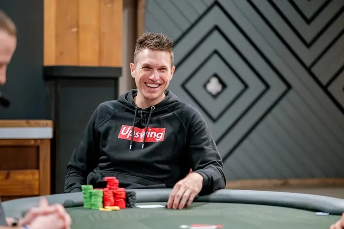 Doug Polk smiling at a poker table wearing an Upswing Poker hoodie during a Lodge Card Club session