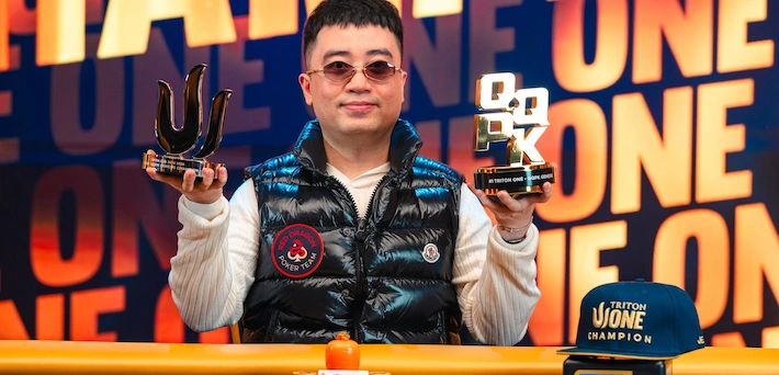 Nguyen Huu Dung, Vietnamese poker pro, holding up two Triton Poker trophies (one horn-shaped, one with "TRITON CHAMPION" plaque) at the Triton Series final table, wearing tinted sunglasses, blue-black puffer vest over white shirt with patches, smiling against an orange-blue "TRITON POKER SERIES CHAMPION" backdrop.